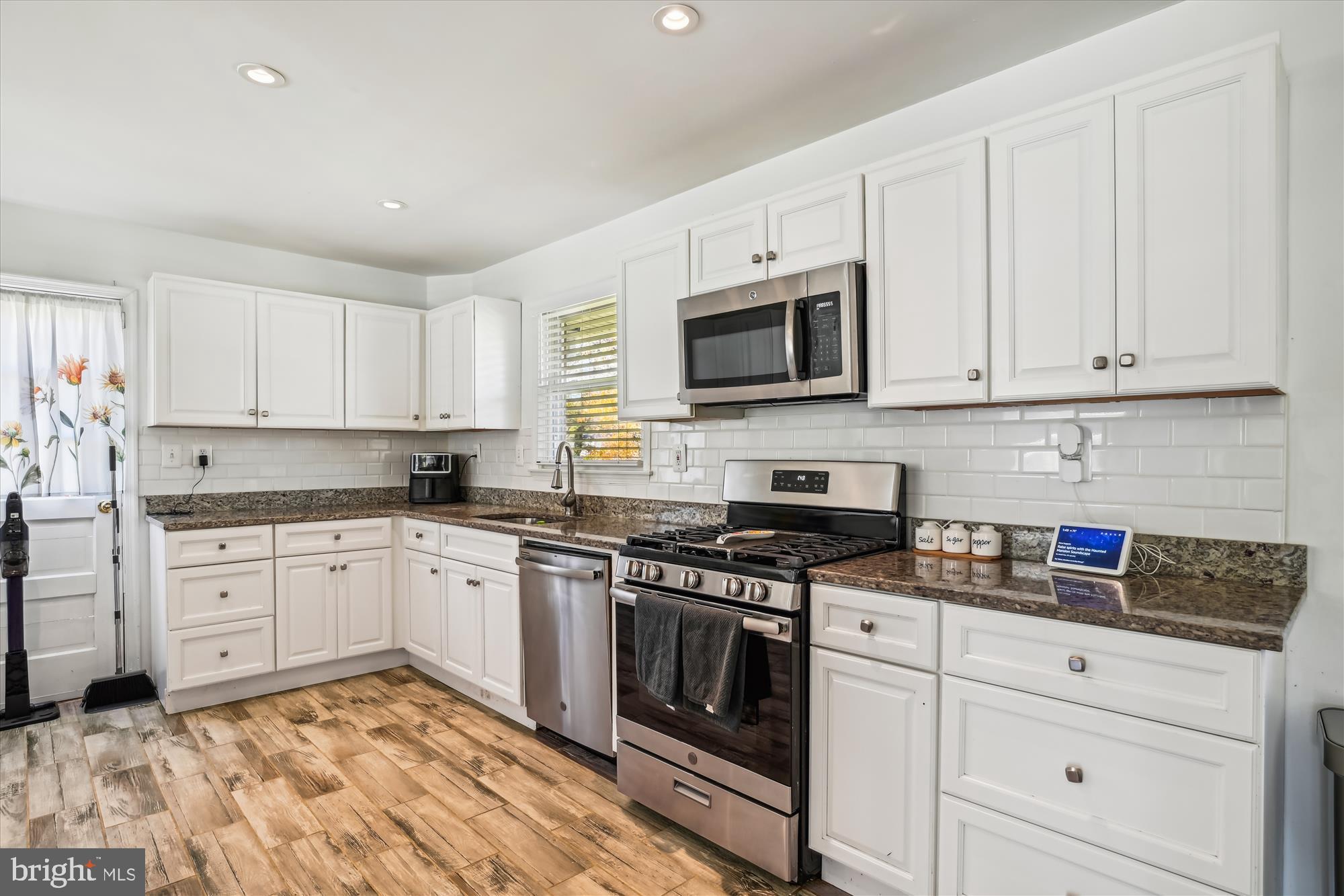 a kitchen with granite countertop white cabinets and stainless steel appliances