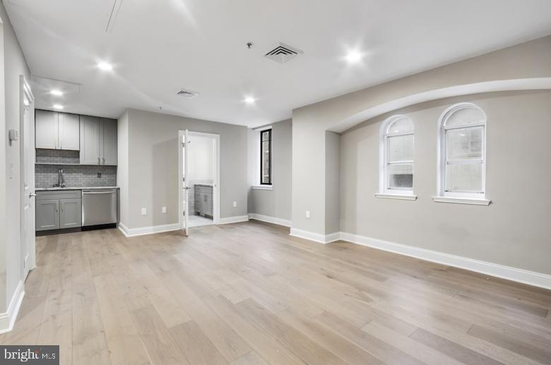 a view of empty room with kitchen and window