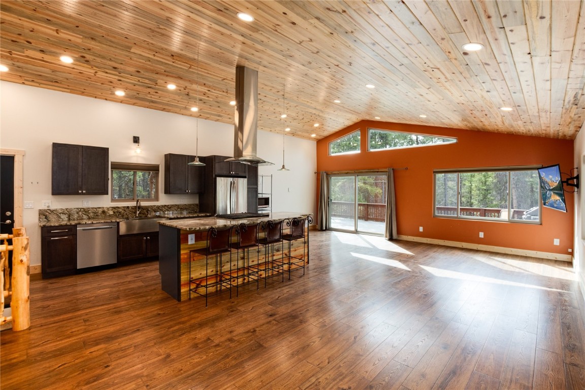 Kitchen with light hardwood / wood-style flooring, high vaulted ceiling, appliances with stainless steel finishes, and a center island