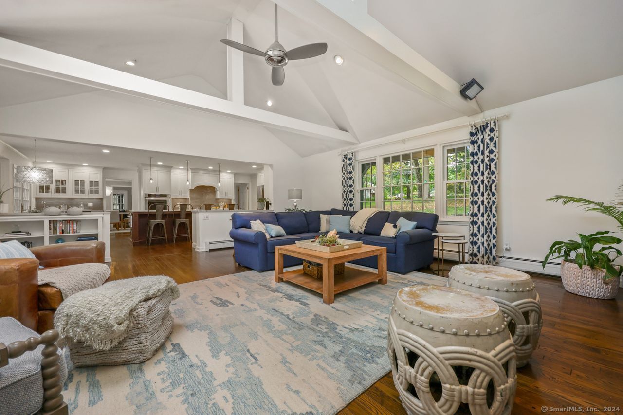 a living room with furniture kitchen view and a large window