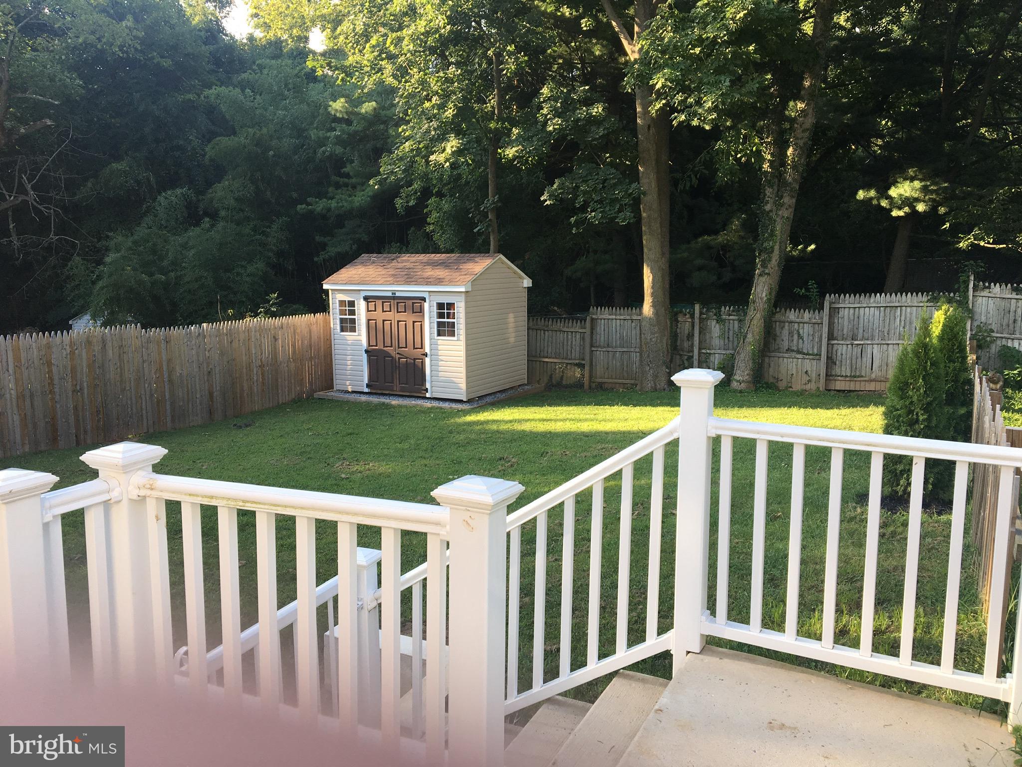 a view of a white house with a small yard and large trees