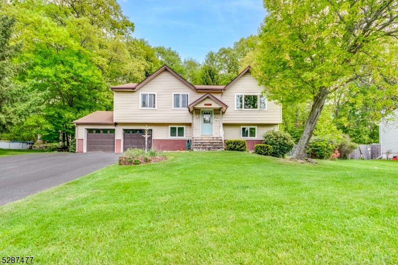 a front view of a house with a garden and trees