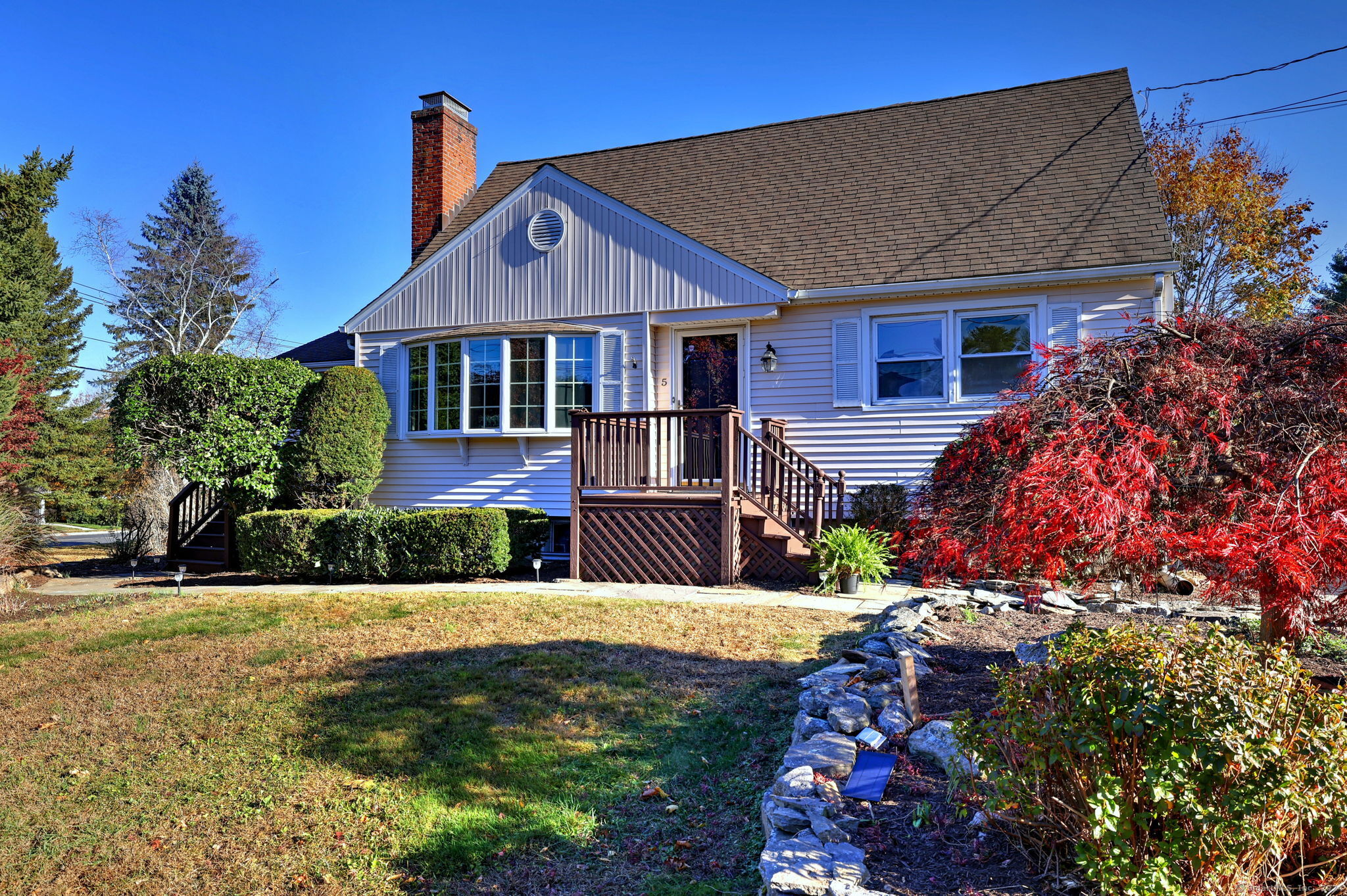 a front view of a house with a yard outdoor seating and covered with trees