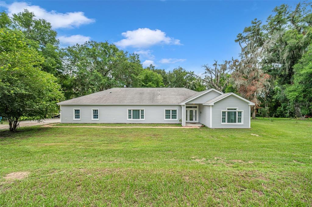 a house that is sitting in a big yard with large trees