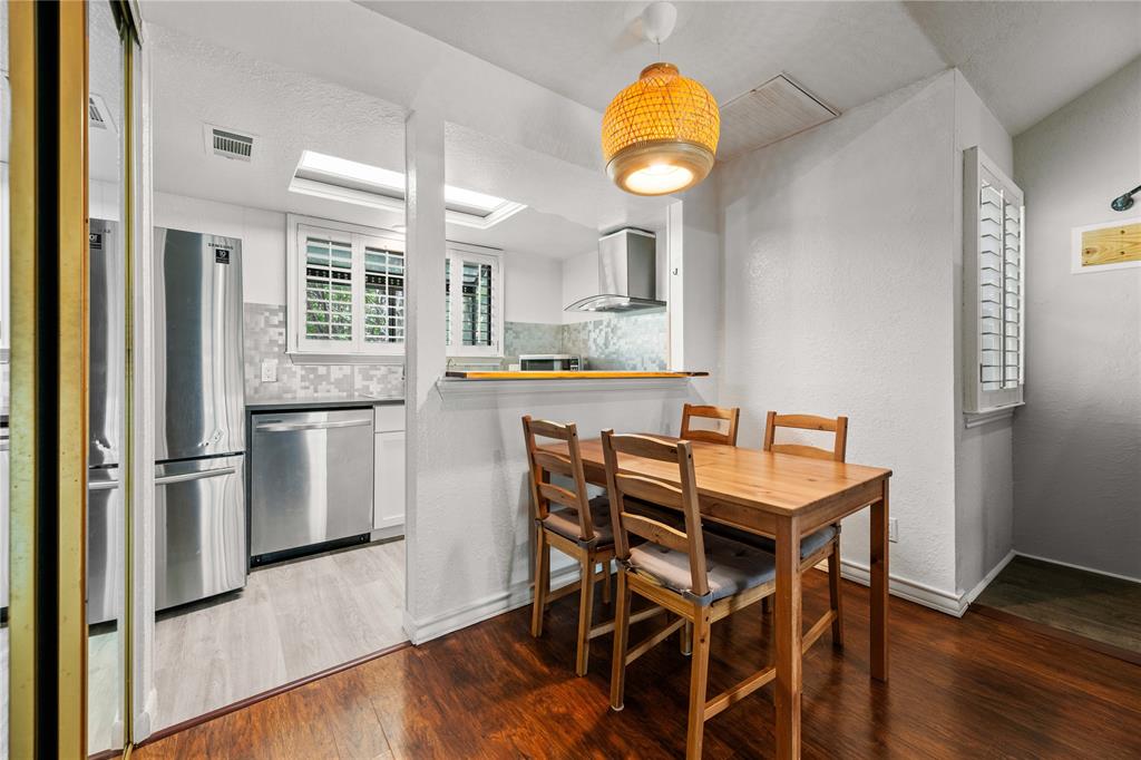 a kitchen with stainless steel appliances kitchen island granite countertop a table chairs sink and cabinets