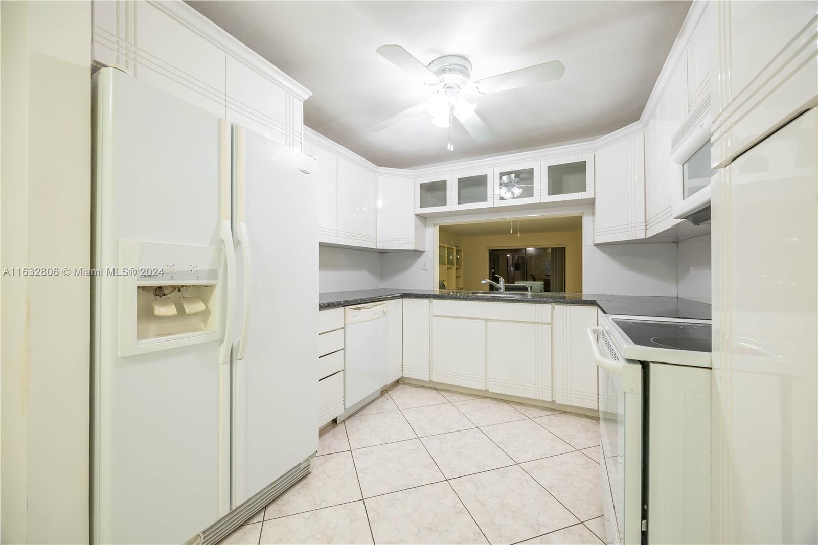 a kitchen with granite countertop a refrigerator and white cabinets