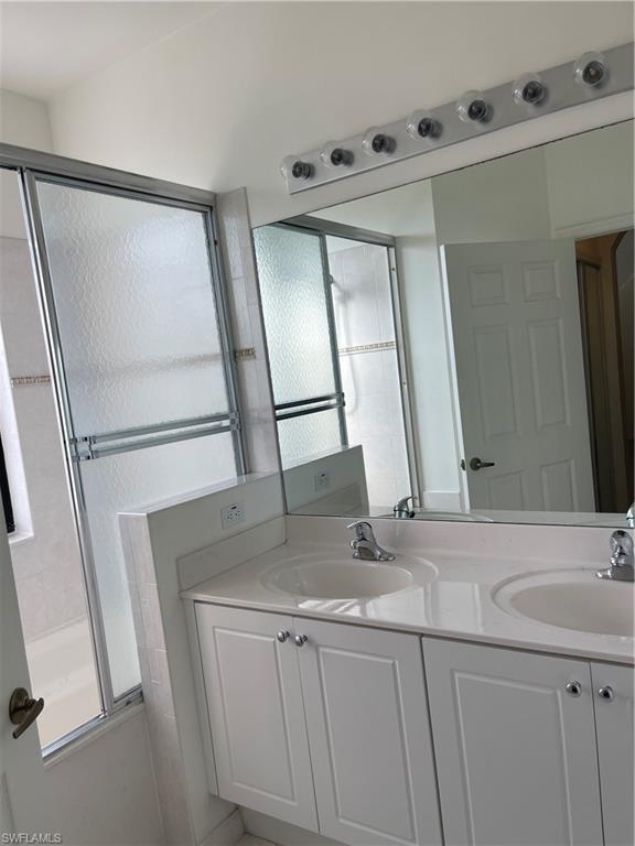 Bathroom featuring vanity and enclosed tub / shower combo