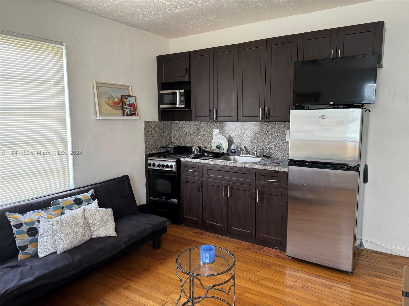 a kitchen with a refrigerator stove and wooden floor