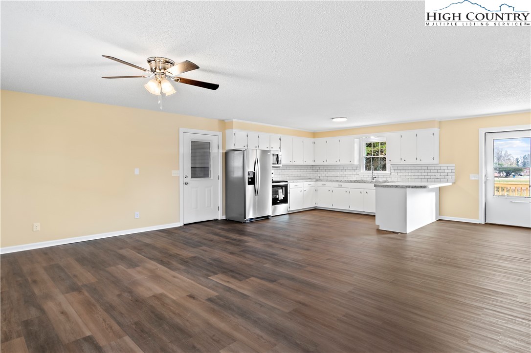 a view of a kitchen with a fridge wooden floor and a window