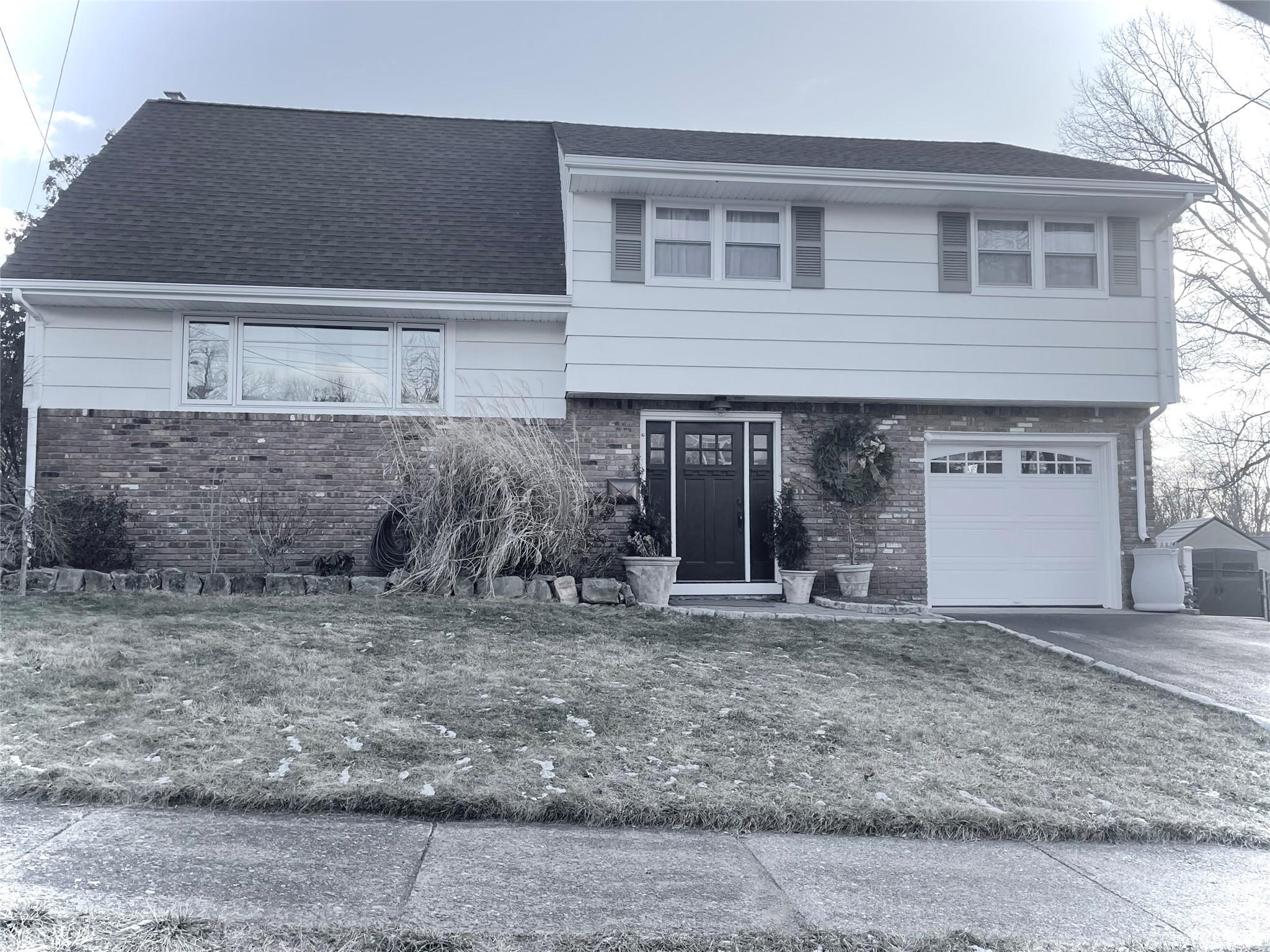 View of front of property with a garage and a front lawn