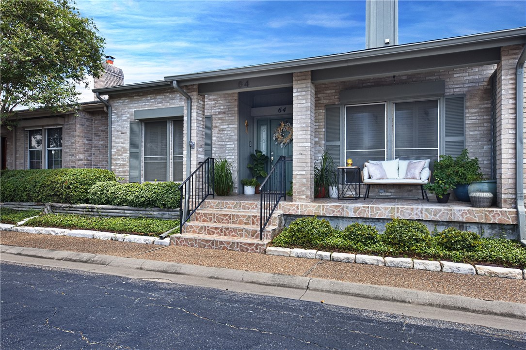 front view of a brick house with a bench and a potted plants