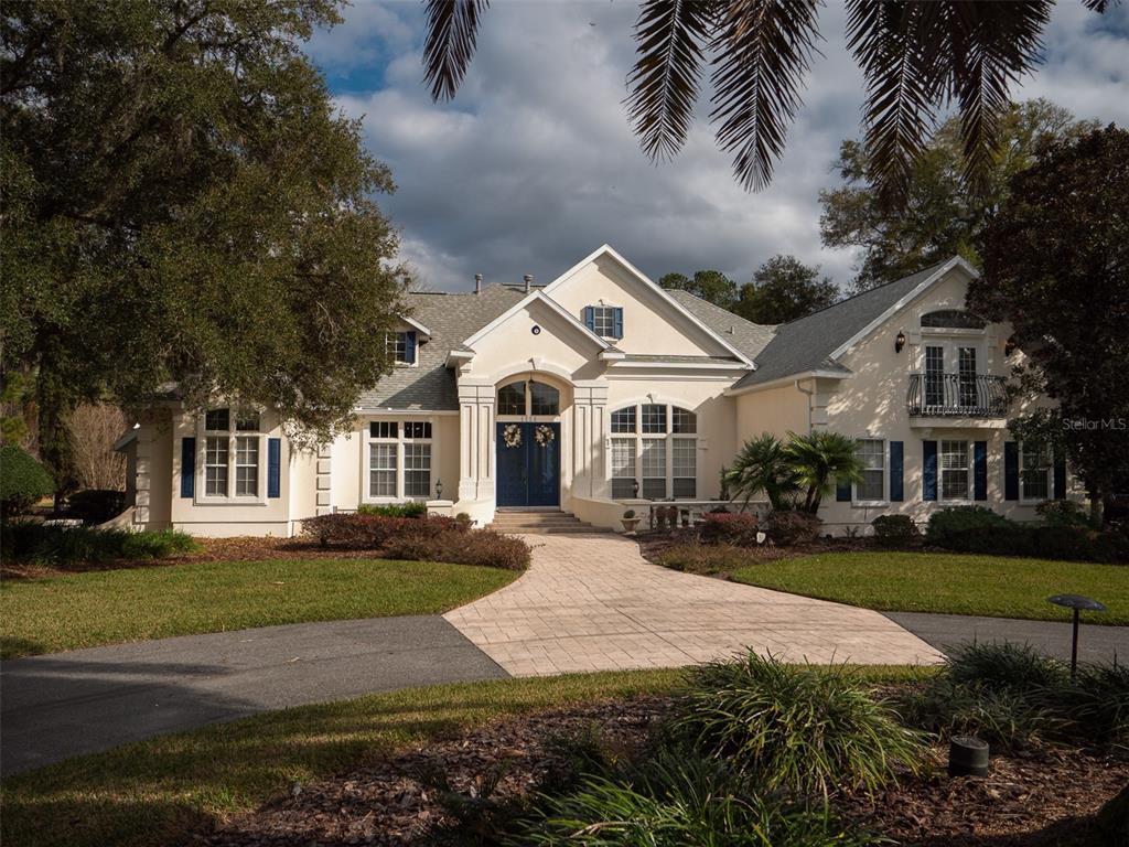 a view of a white house next to a yard with palm trees