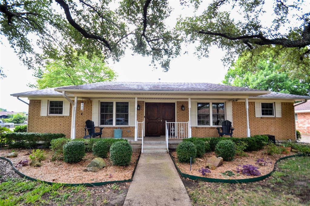 a front view of a house with plants and trees