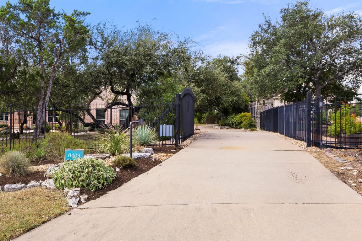 Private gated entrance to the property features an electric gate and plenty of driveway space for multiple vehicles. The yard is xeriscaped and manicured.