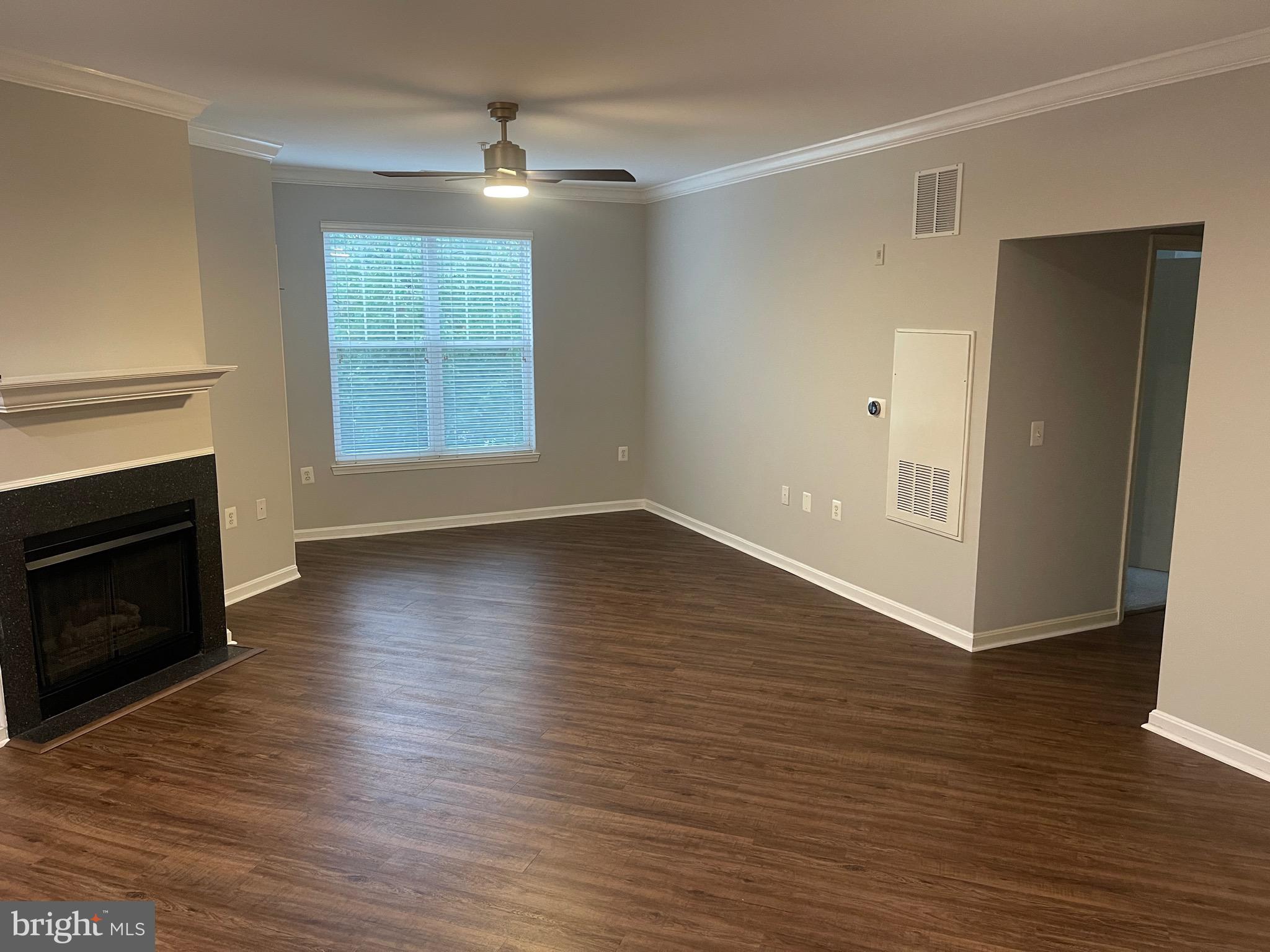 an empty room with wooden floor fireplace and windows