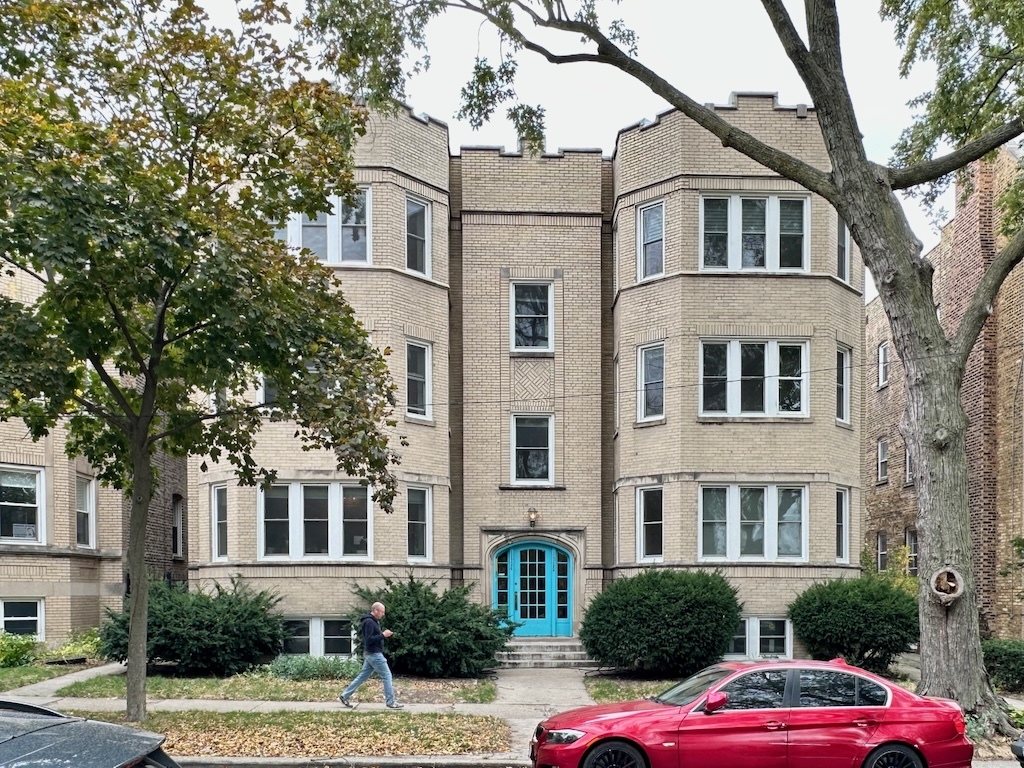 a front view of a building with lot of cars parked on road