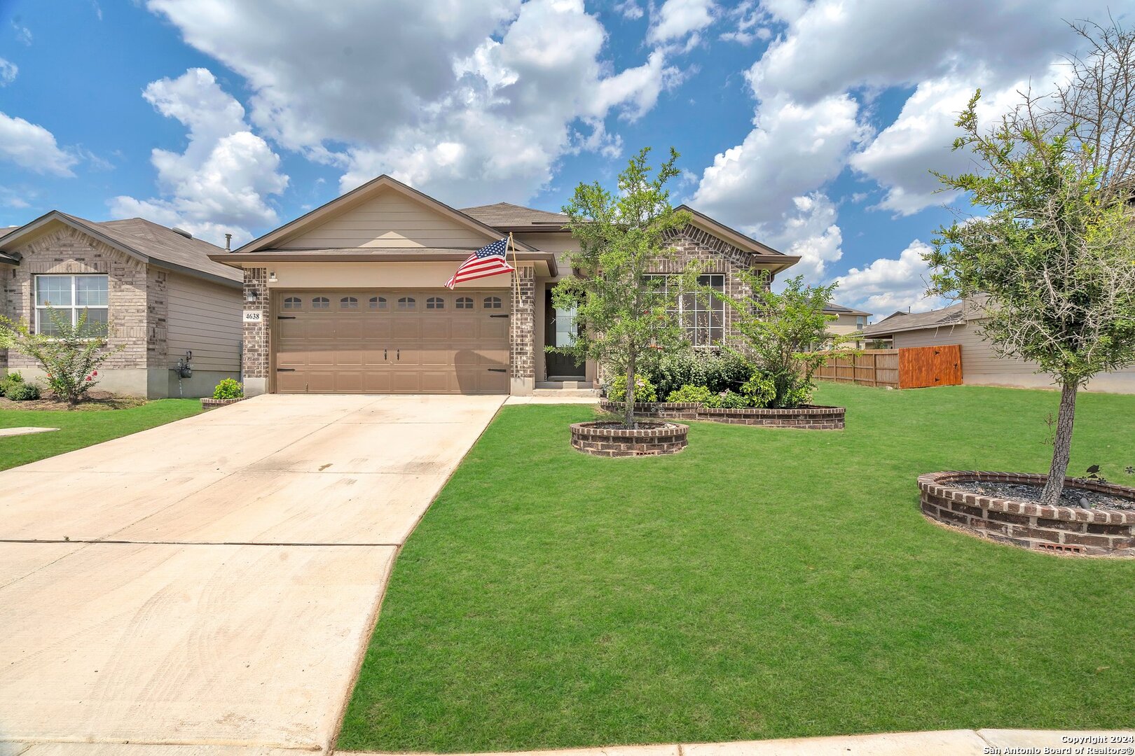 a front view of a house with a garden and a tree