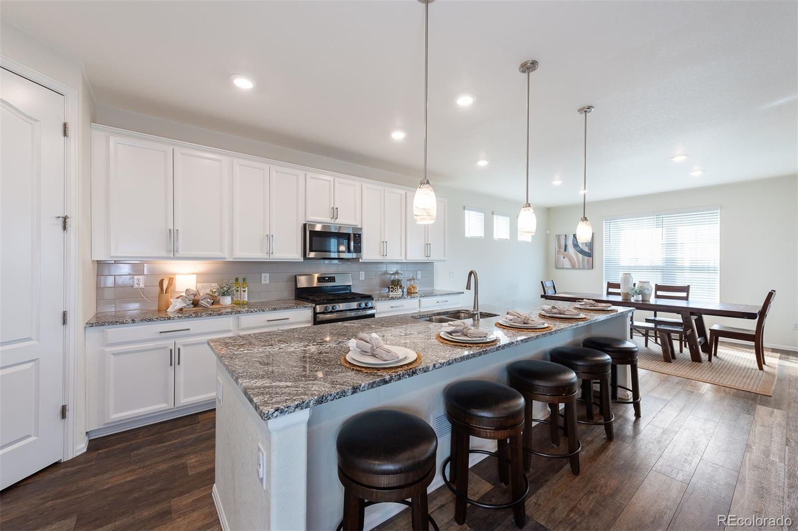 a kitchen with kitchen island granite countertop a table chairs sink and cabinets