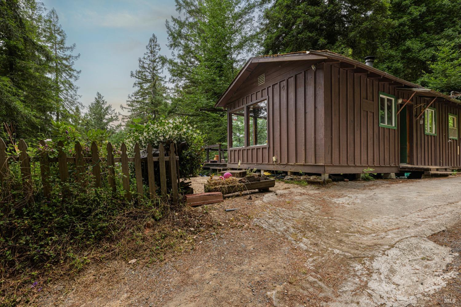 a view of backyard of house with wooden fence and trees