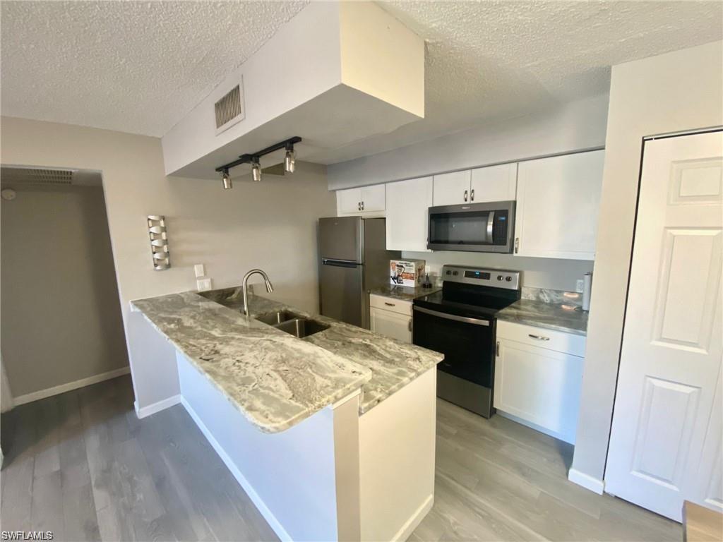 a kitchen with granite countertop a refrigerator stove and sink