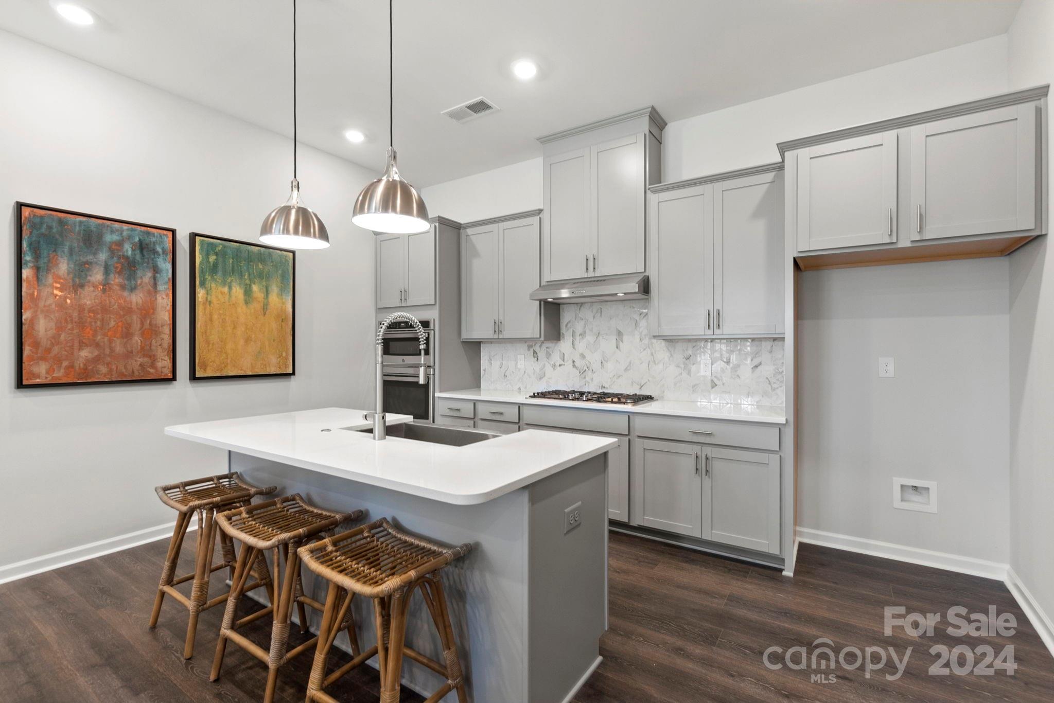 a kitchen with a sink a stove a refrigerator and white cabinets