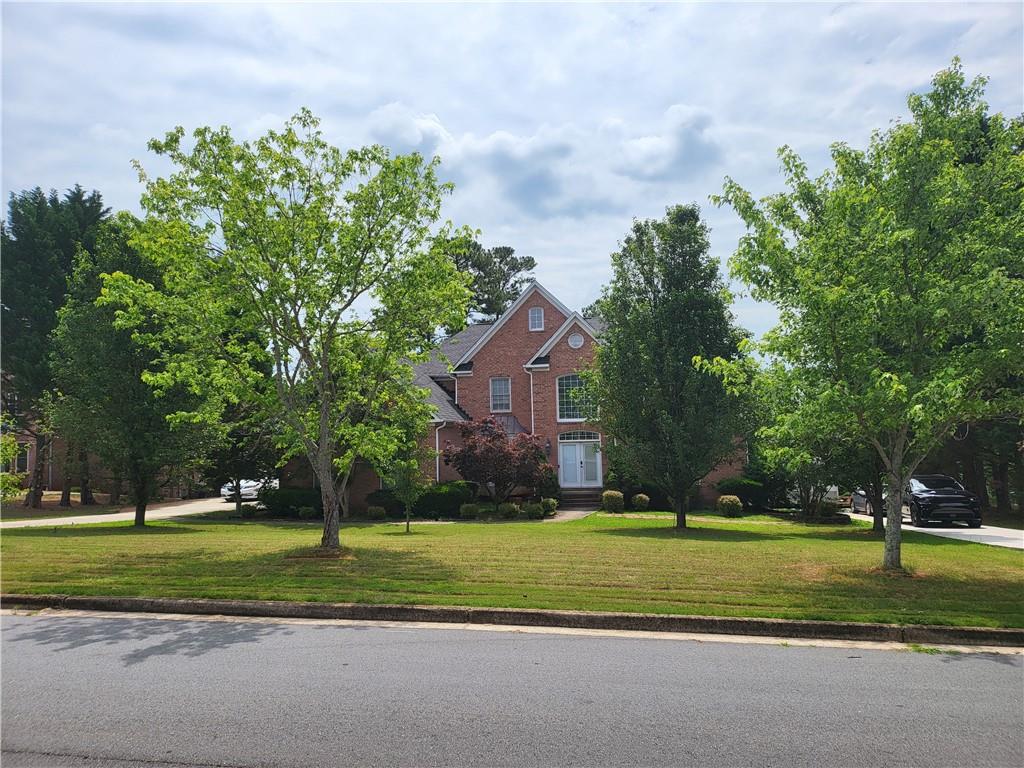 a view of a house with a big yard and large trees