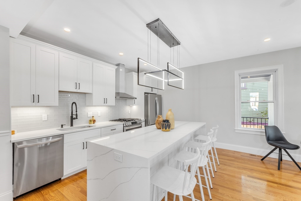 a kitchen with a sink a stove a refrigerator and white cabinets with wooden floor