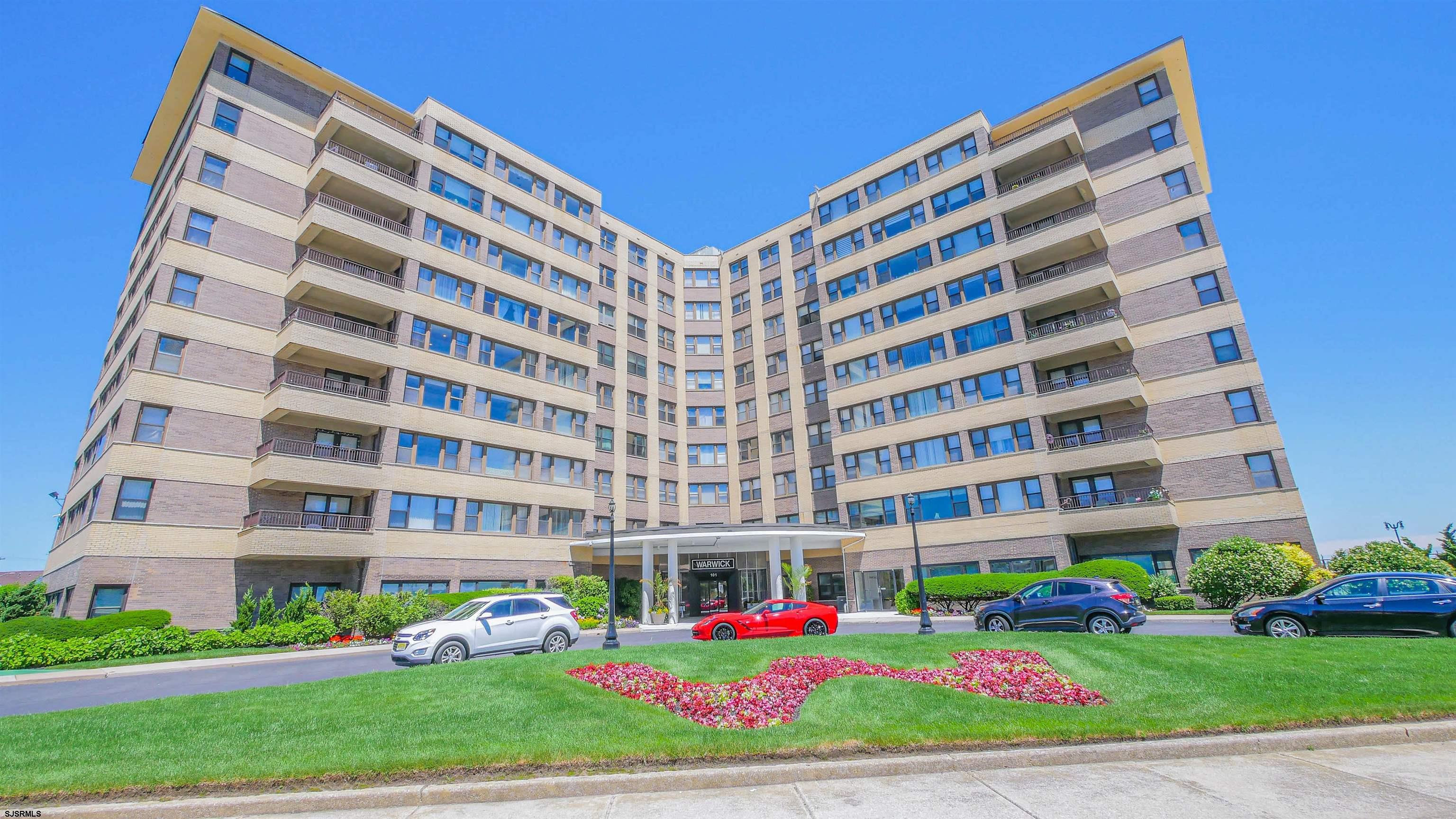 a front view of multi story residential apartment building with yard and green space