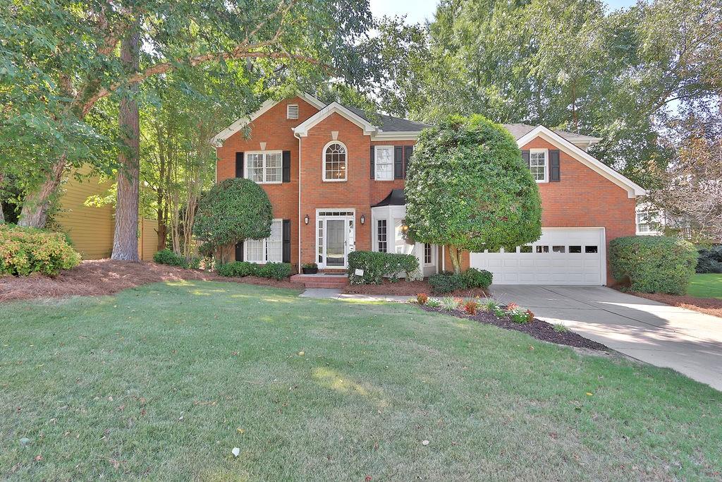 a front view of a house with a garden and yard