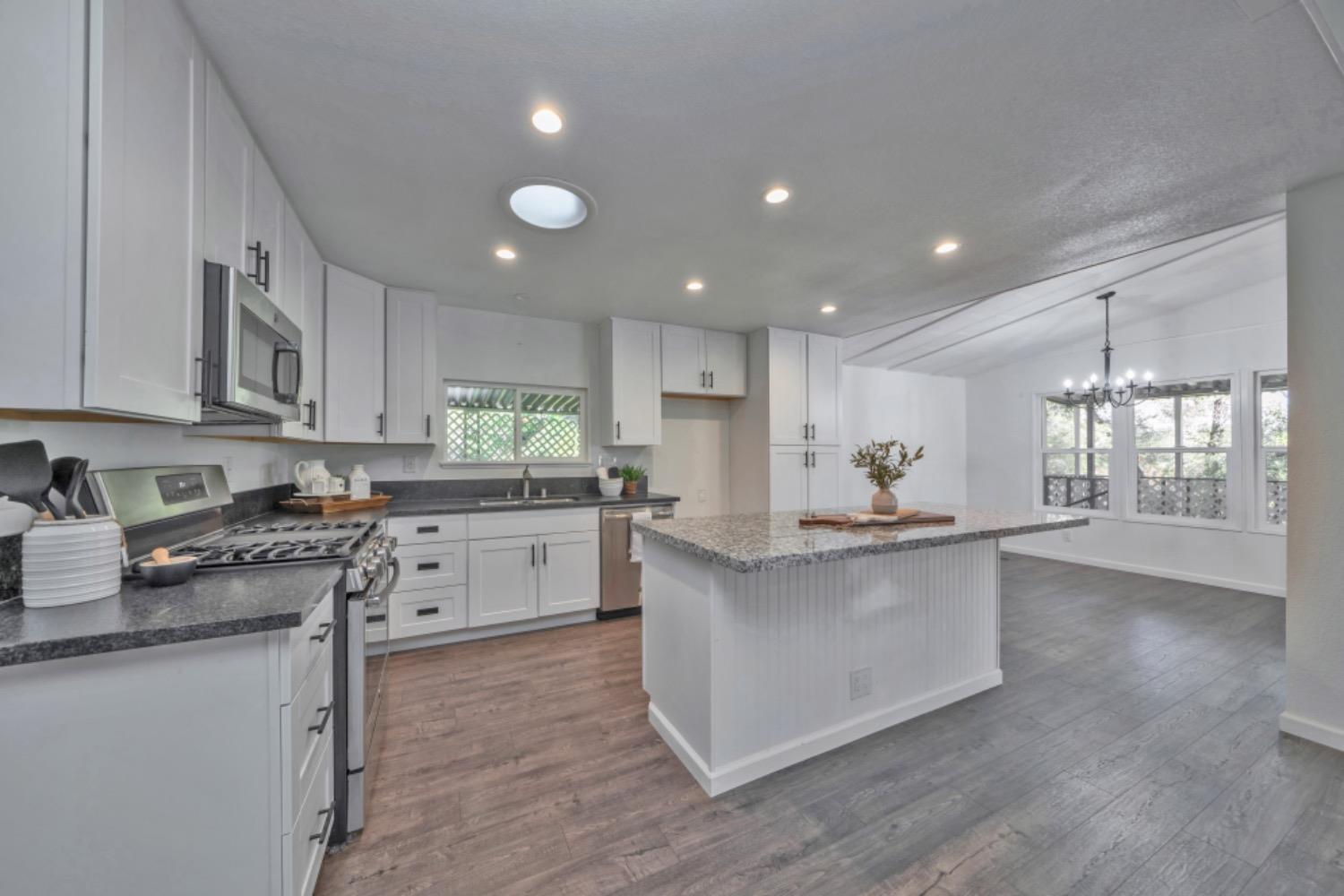 a kitchen with stainless steel appliances granite countertop a stove a sink and white cabinets