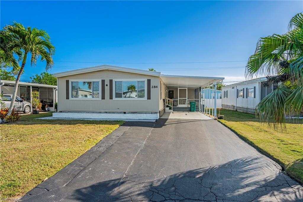 Manufactured / mobile home featuring a front yard and a carport