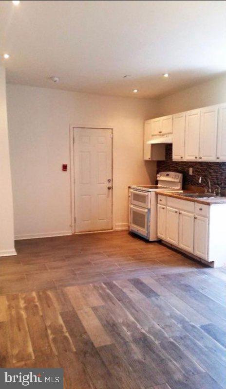 a view of a kitchen with a sink and dishwasher a stove top oven with wooden floor