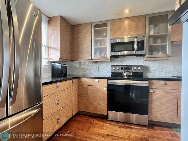 a kitchen with stainless steel appliances granite countertop a stove a sink and a refrigerator