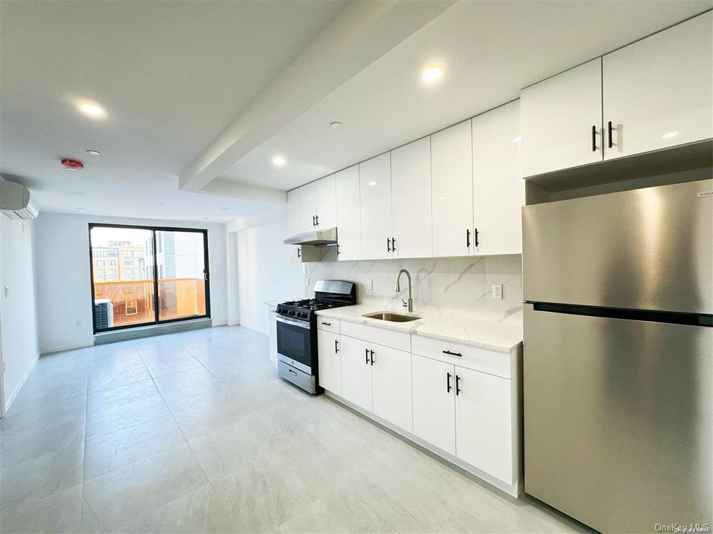 Kitchen with tasteful backsplash, stainless steel appliances, a wall unit AC, sink, and white cabinetry