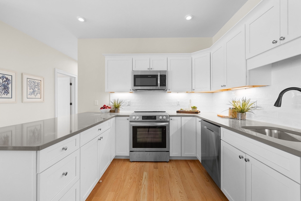 a kitchen with granite countertop white cabinets stainless steel appliances and a sink