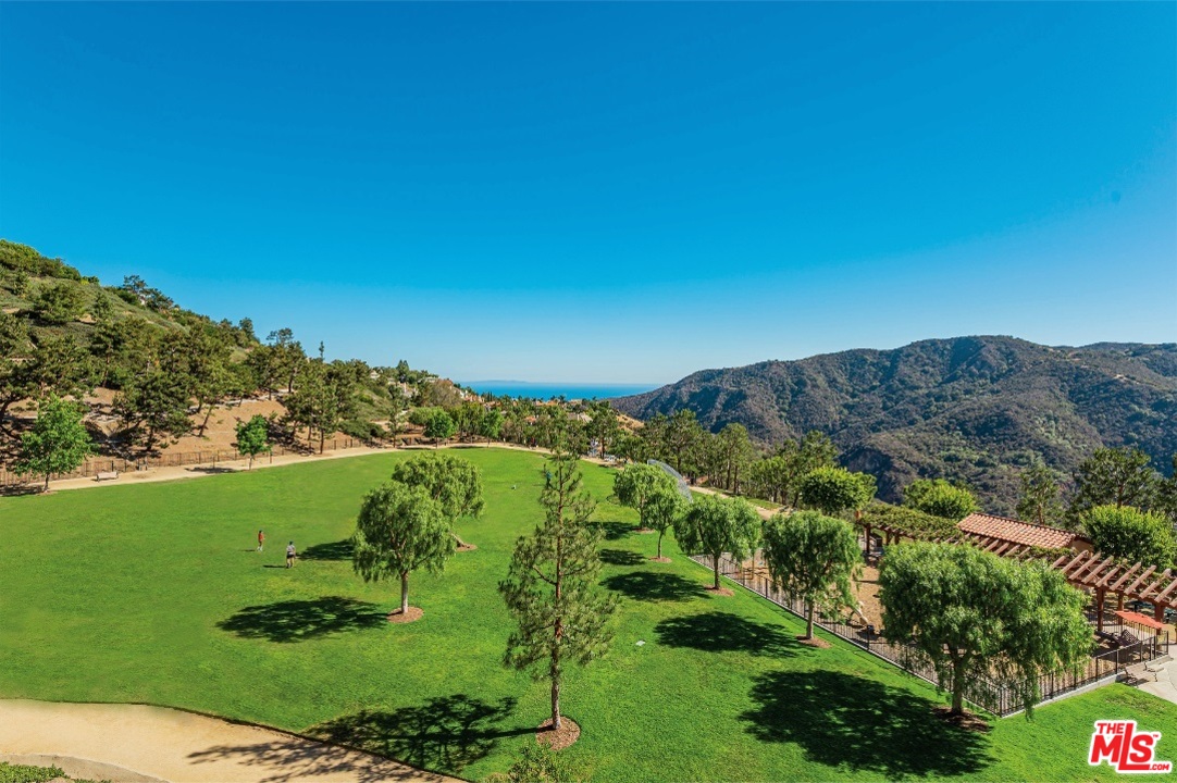 a view of a grassy area with mountains and a couple of people