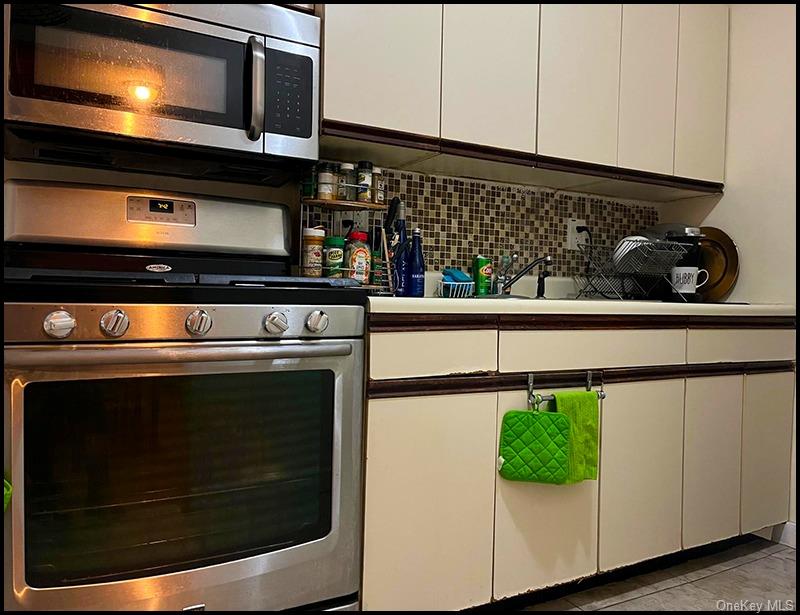 Kitchen featuring stainless steel appliances, backsplash, and white cabinets