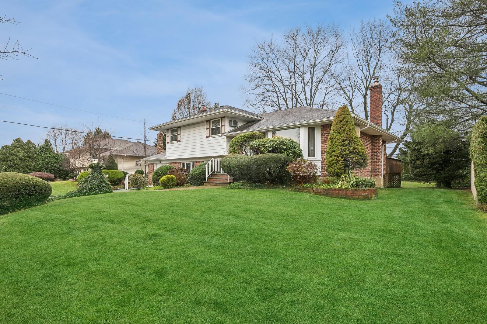 a view of a house with a big yard potted plants and large tree