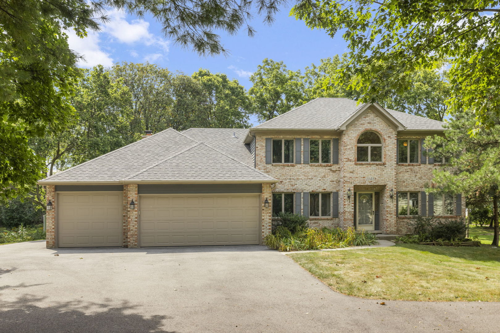 a front view of a house with a garden and trees