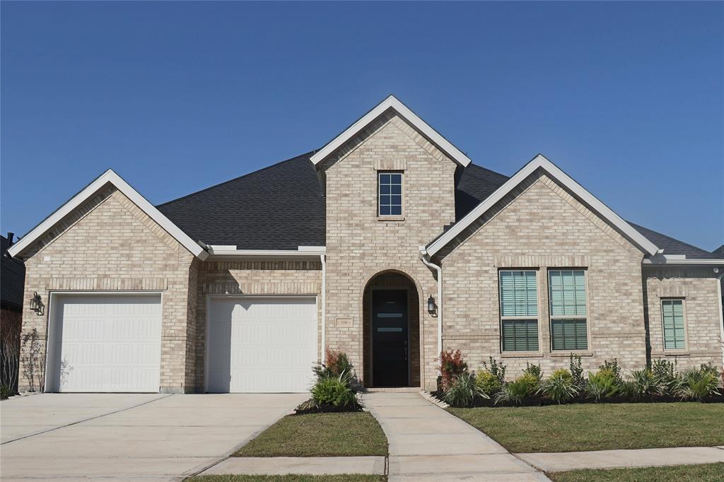 This is a modern single-story brick home featuring a prominent gable roof and a landscaped front yard.