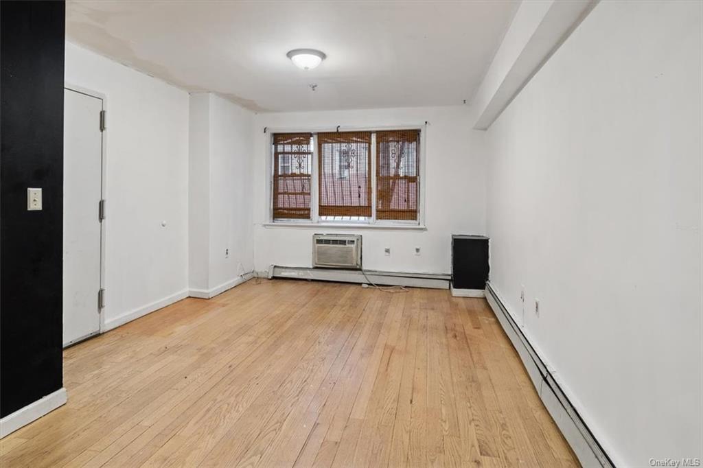 Spare room with light hardwood / wood-style flooring, baseboard heating, and an AC wall unit