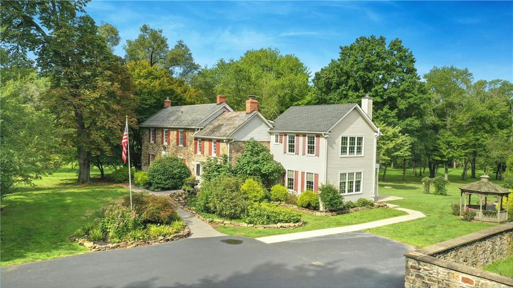 a view of a white house next to a yard with big trees