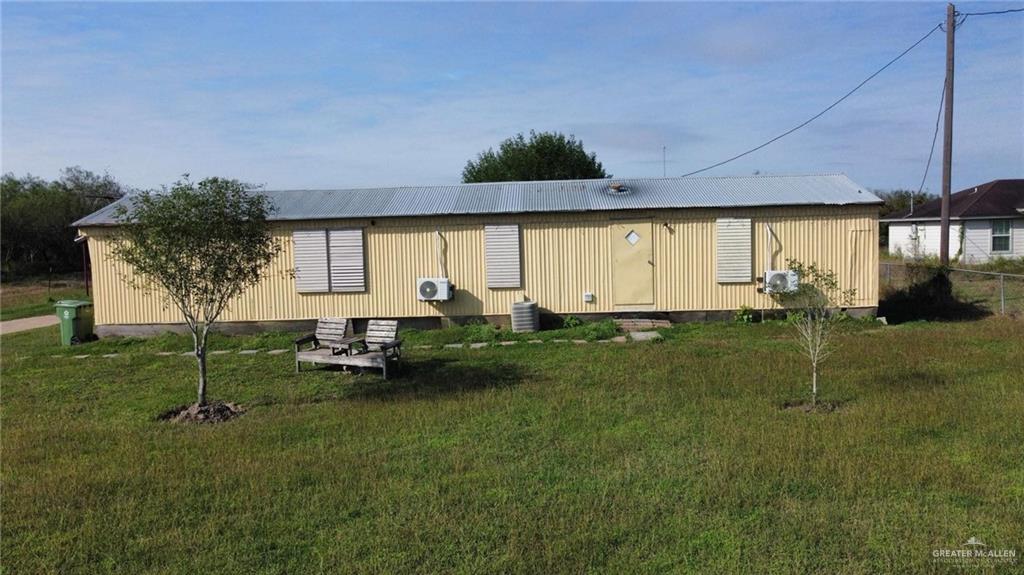 Back of house with a yard and central air condition unit