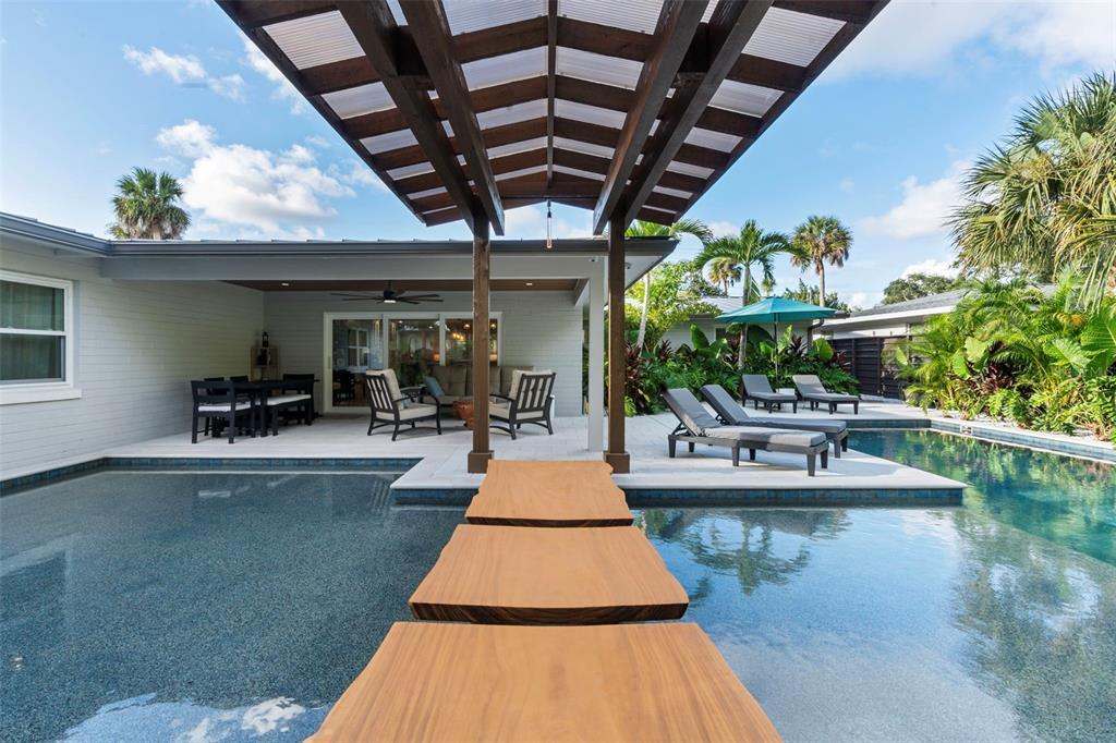 a swimming pool with outdoor seating and potted plants