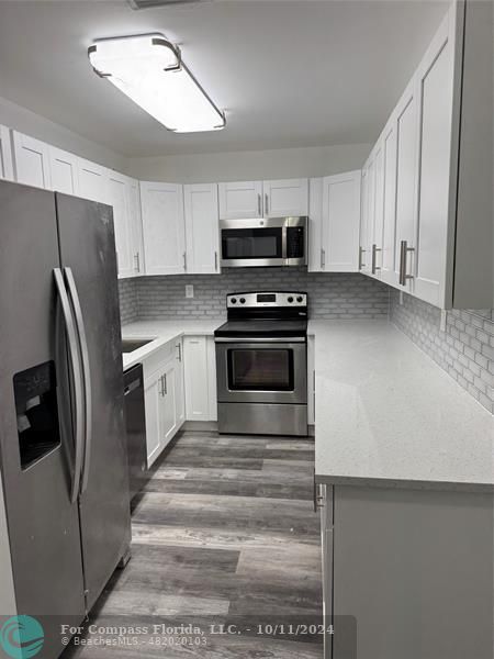 a kitchen with stainless steel appliances a refrigerator sink and white cabinets