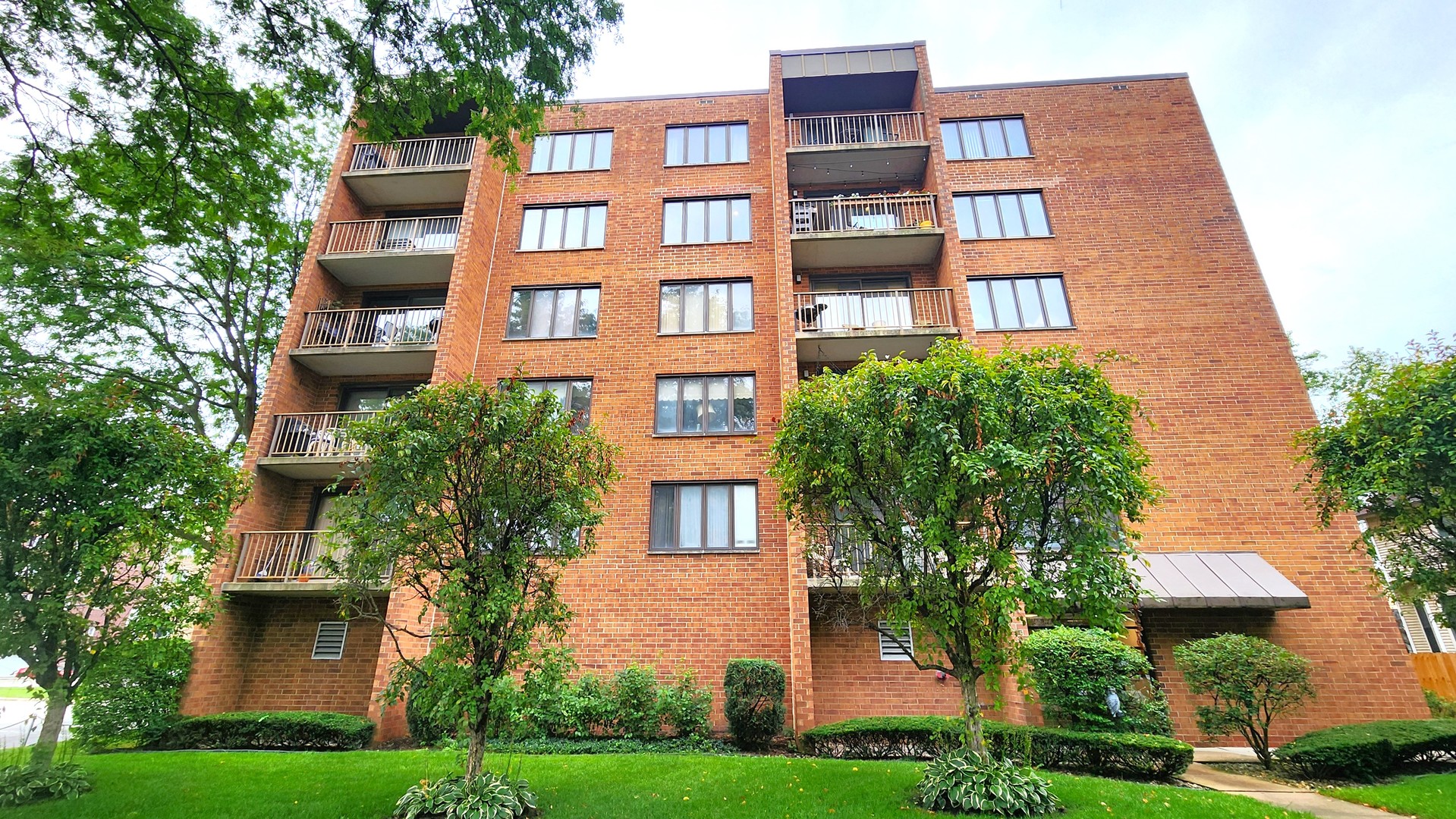 a front view of a multi story building with yard