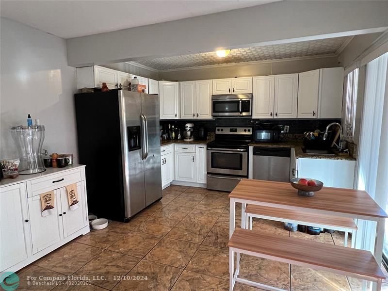 a kitchen with stainless steel appliances granite countertop a refrigerator stove and sink