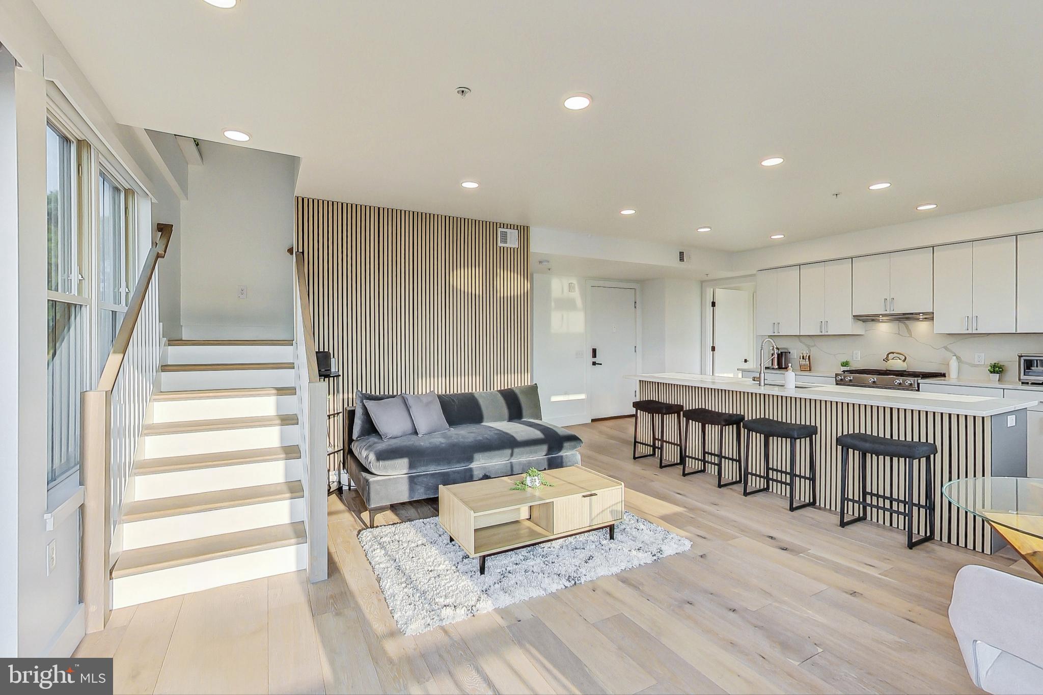 a living room with stainless steel appliances furniture and a wooden floor