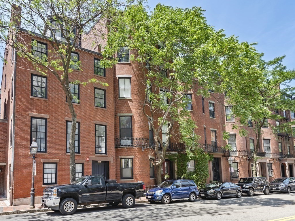 a front view of a building with lot of cars parked on road