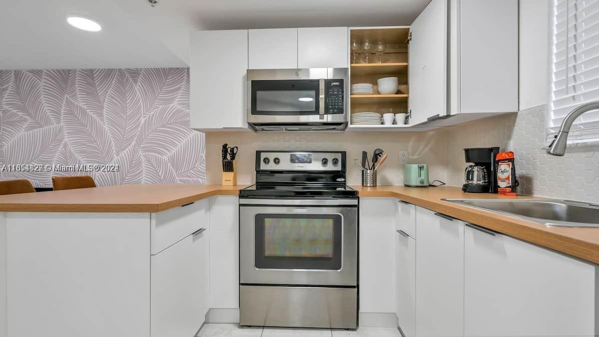 a kitchen with stainless steel appliances granite countertop a stove a microwave and a sink